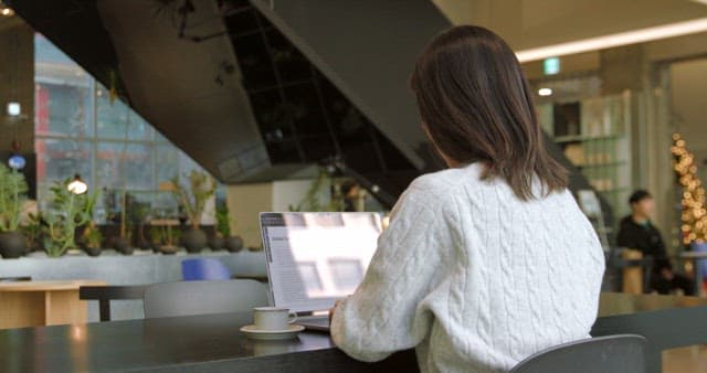 Woman Working on Laptop in a Modern Cafe