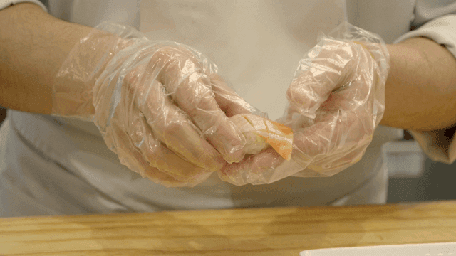 Chef carefully prepares salmon sushi.