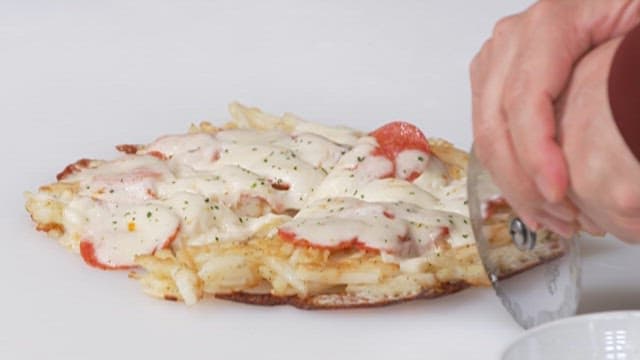 Hand Cutting Freshly Baked Cheese Potato Pancake with Pizza Cutter