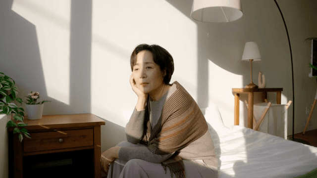 햇살이 비치는 침대에 앉아 있는 여성