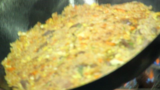 Pan-fried fried rice being plated on a plate