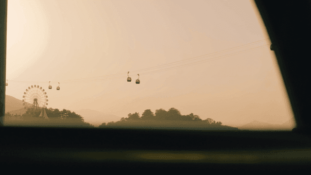 Cable cars and Ferris wheels passing over evening sky