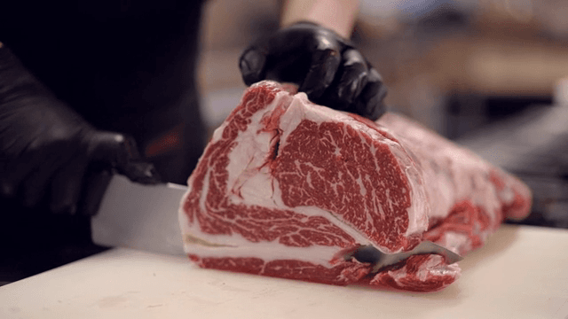 마블링이 있는 큰 소고기 덩어리를 자르는 모습