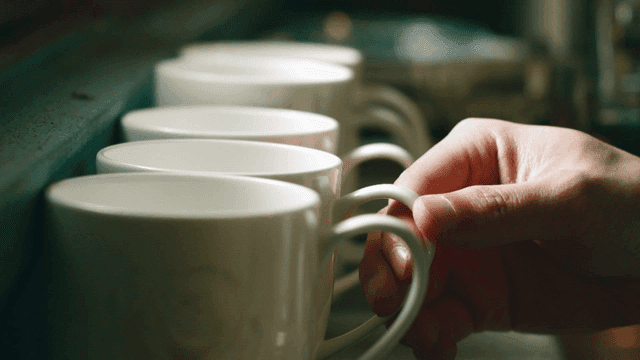 Hands arranging coffee cups
