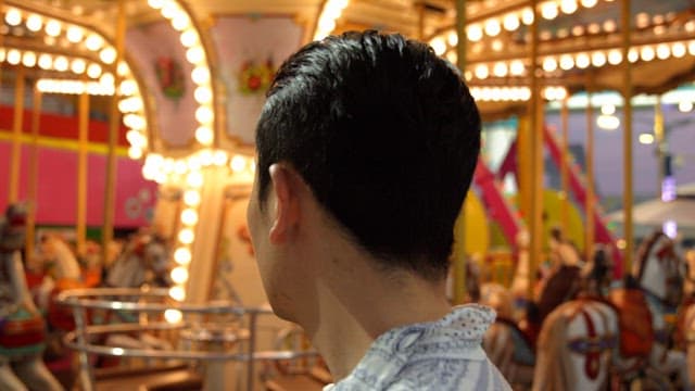 Man at a colorful carousel in an amusement park