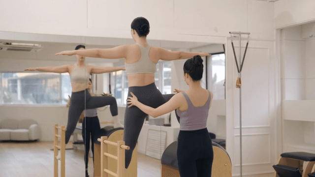 Pilates instructor guiding a student indoors