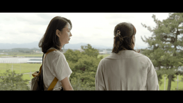 Two women talking in front of tree