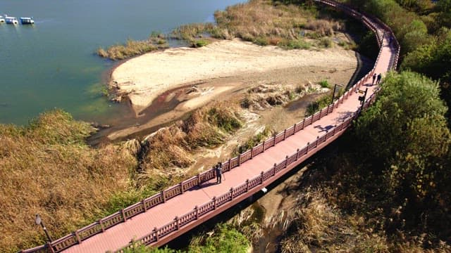 People walking on a wooden trail near Baegunhosu Lake, surrounded by mountains