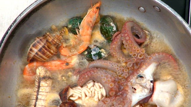 Various seafood such as octopus and abalone boiling in a pot