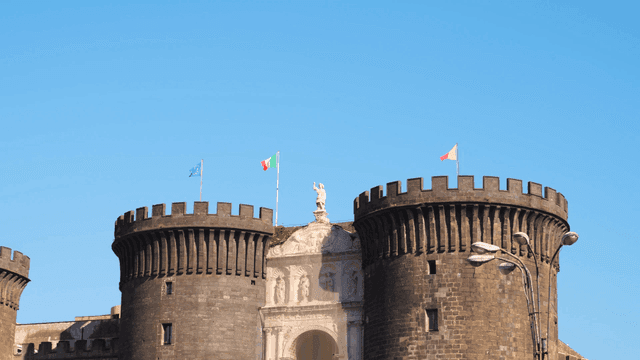 Historic castle with flags under clear sky