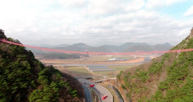 Scenic View of Red Suspension Bridge Over Landscape