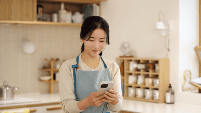 A woman in an apron using a smartphone
