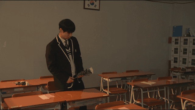 Boy in classroom holding chrysanthemums