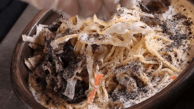 Sprinkling black sesame powder on cream pasta