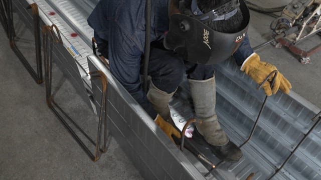 Worker welding metal beams indoors