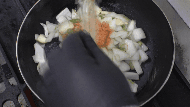 팬에서 볶아지는 채소들에 부어지는 특별 조미료 가루