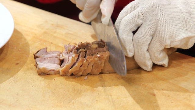 Slicing boiled pork on a wooden board