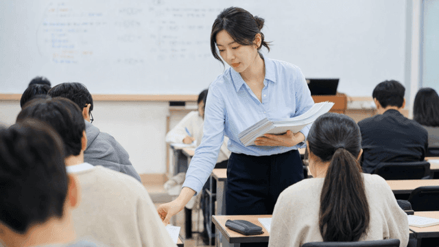 Teacher distributing documents in classroom