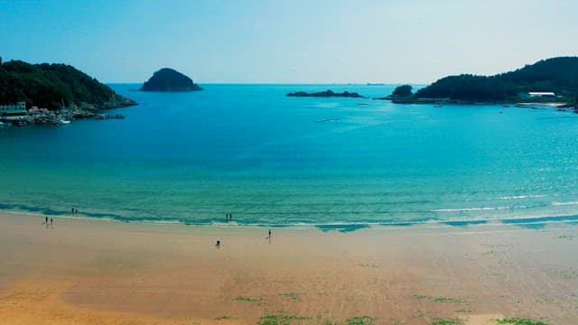 고요한 에메랄드 빛 바닷가를 거니는 사람들