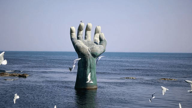 바다에 있는 부두와 큰 손 조각상