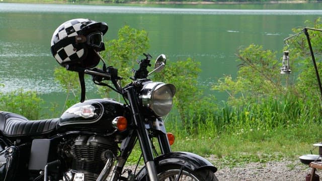 Black motorcycle parked on a grassy lakeside