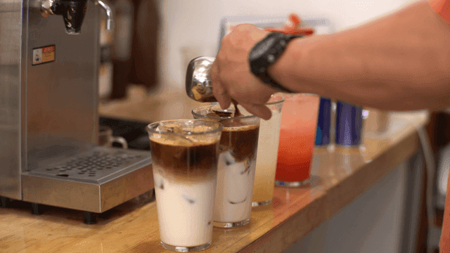 바리스타가 아이스 라떼에 커피를 붓는 모습