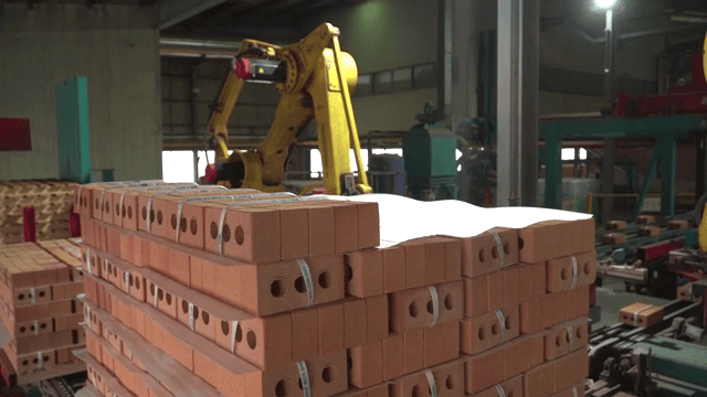 Robotic arm stacking bricks in a factory