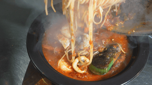 Seafood pasta being prepared in a pan