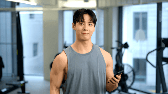 헬스장에서 스마트폰을 보며 덤벨 운동하는 젊은 남성