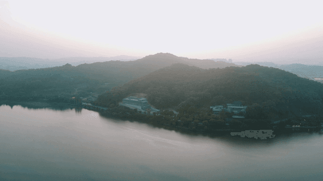 Sun rising over tranquil lake surrounded by hills