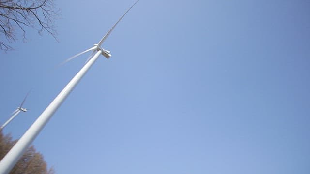 White wind turbines spinning under the blue sky