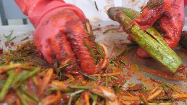 Making cucumber kimchi by hand with red gloves