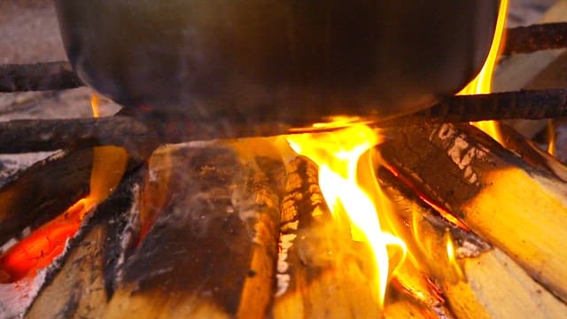 Pot with boiling fish soup over an open flame