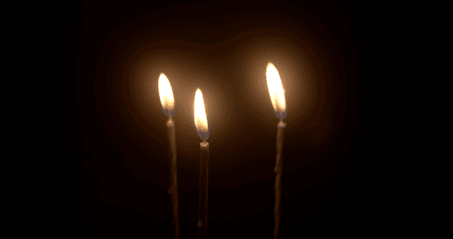 Three lit candles in the dark