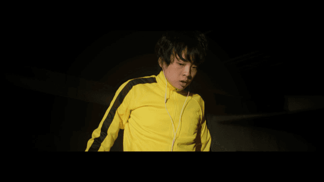 노란 트레이닝복을 입고 이어폰을 낀 남자