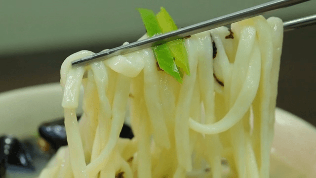 Picking up noodles in noodle soup with chopsticks