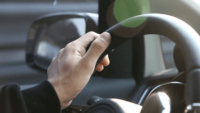 Hand gripping a car steering wheel