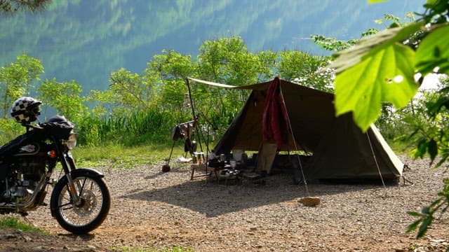 Campsite by a serene lake at sunny afternoon with motorbike and tent