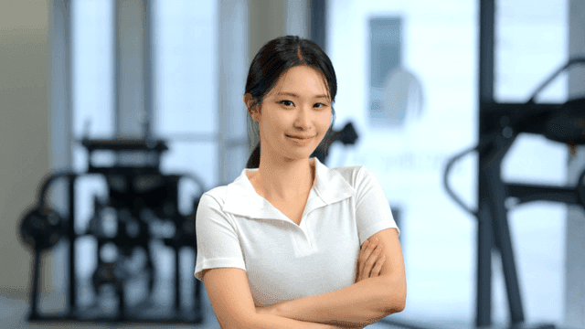 체육관에서 자신감 있게 정면을 보고 미소 짓는 여성