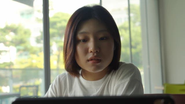 Woman drinking a drink while looking at a screen in a cafe