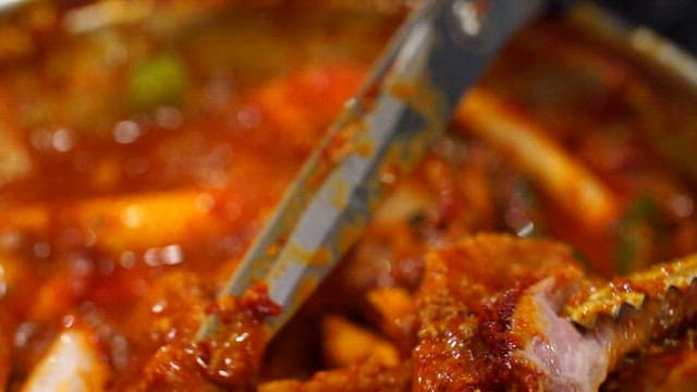 가스레인지에서 끓고 있는 매운갈비찜의 고기를 자르기