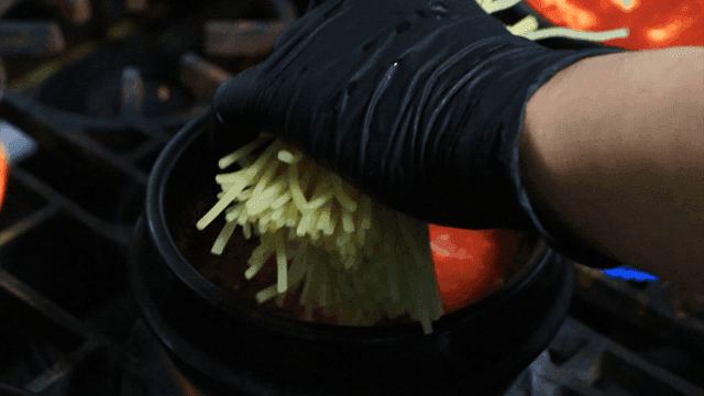 Adding chewy noodles to boiling soft bean curd jjigae