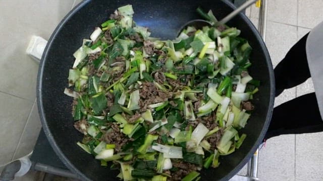 Cooking beef bulgogi with green onions in a pan