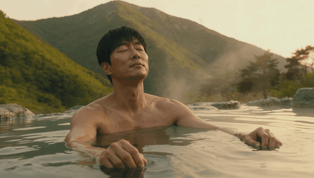 산을 배경으로 야외 온천에서 휴식하는 남성