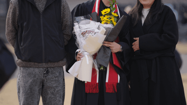 Graduates and their parents holding bouquets