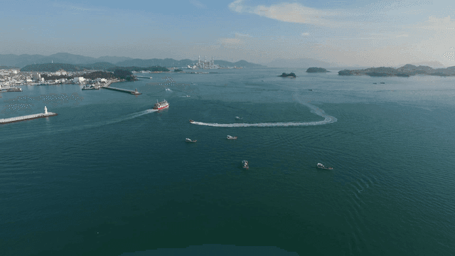 다양한 선박들과 먼 산이 있는 해안 마을