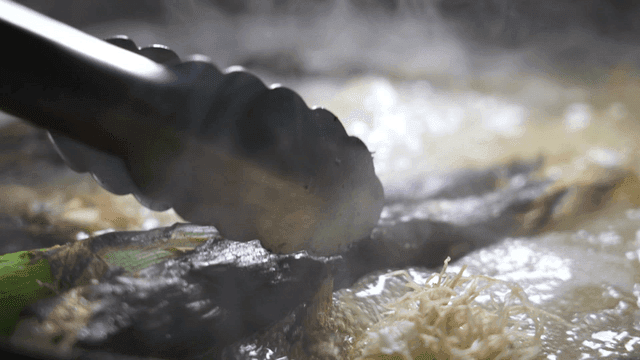 Grilled green onions added to boiling broth