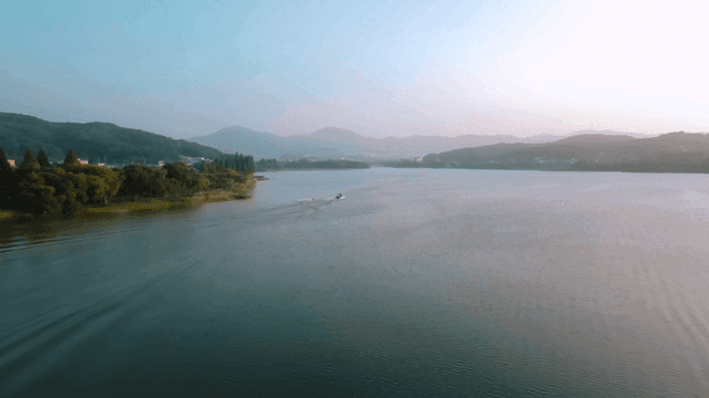 Boat crossing lake where sun rises
