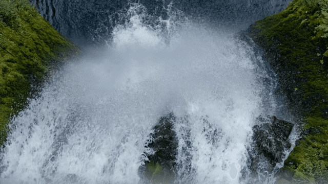 Water cascading down a lush green cliff