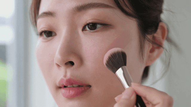 Woman applying pink blush with brush